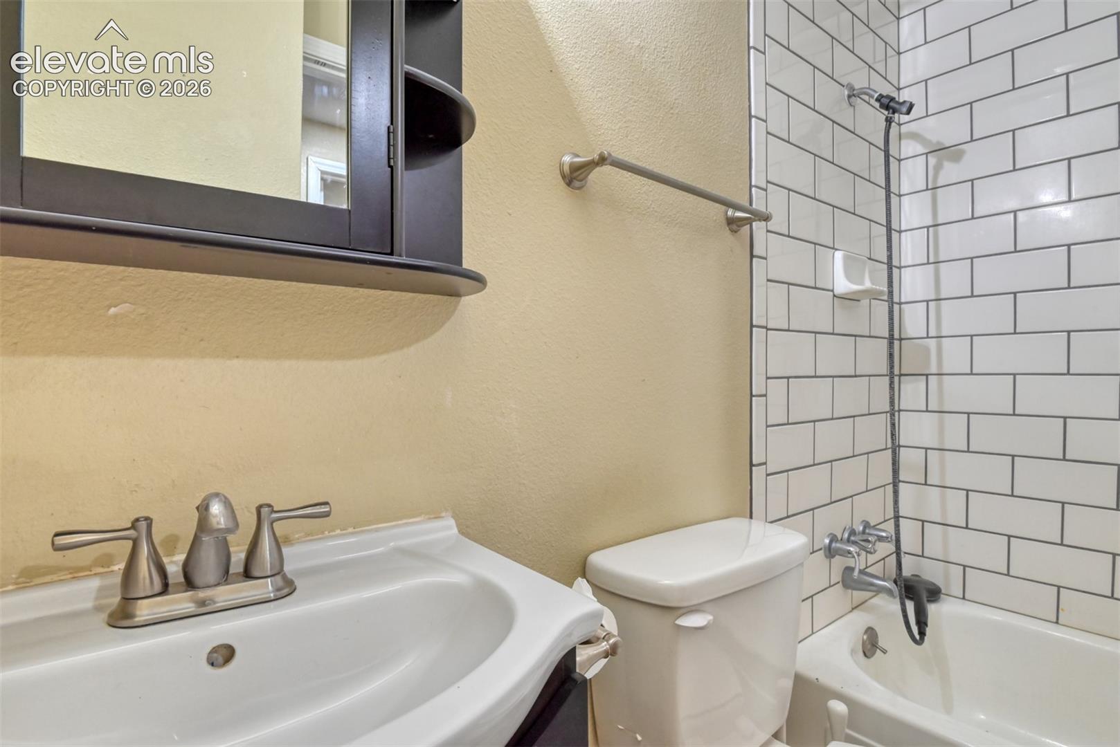 Bathroom featuring a white ceramic sink, a dark wood-finish medicine cabinet with shelving, and a toilet