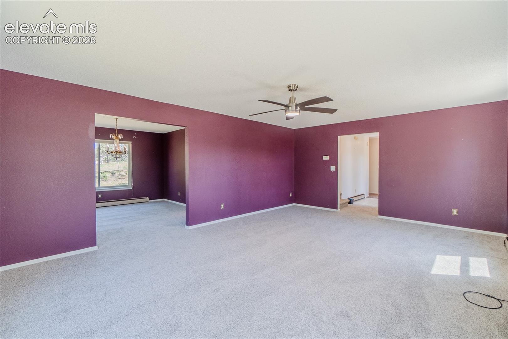 Carpeted flooring throughout, recessed archways, and a ceiling fan with integrated lighting