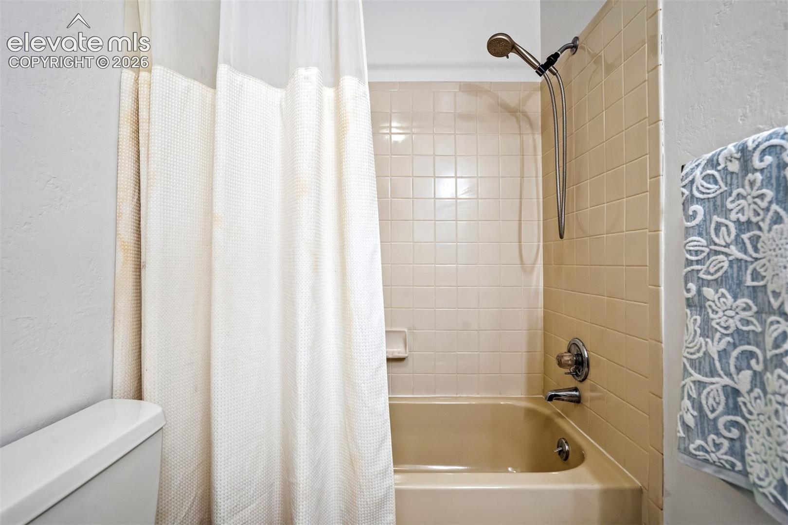 Bathroom featuring a shower/tub combination with beige subway tile surround and brushed nickel fixtures