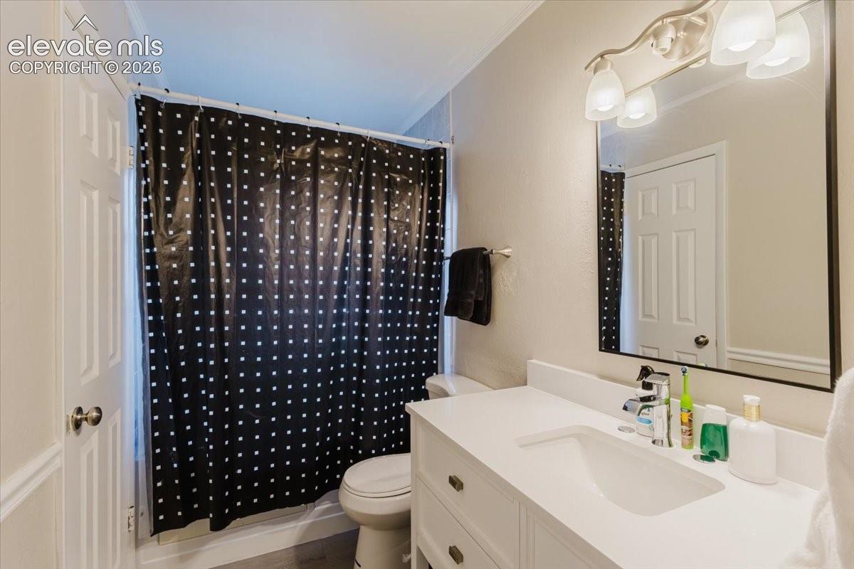 Bathroom featuring a white vanity with integrated sink, chrome faucet, wall-mounted mirror, and a three-light fixture