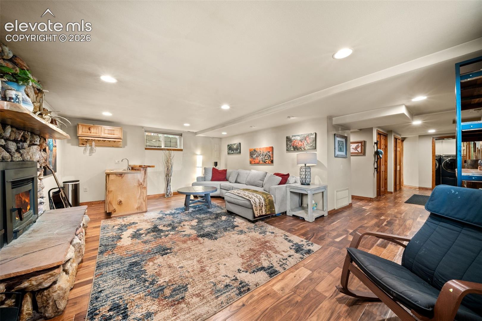 Spacious lower-level living area with a cozy stone fireplace and wet bar.