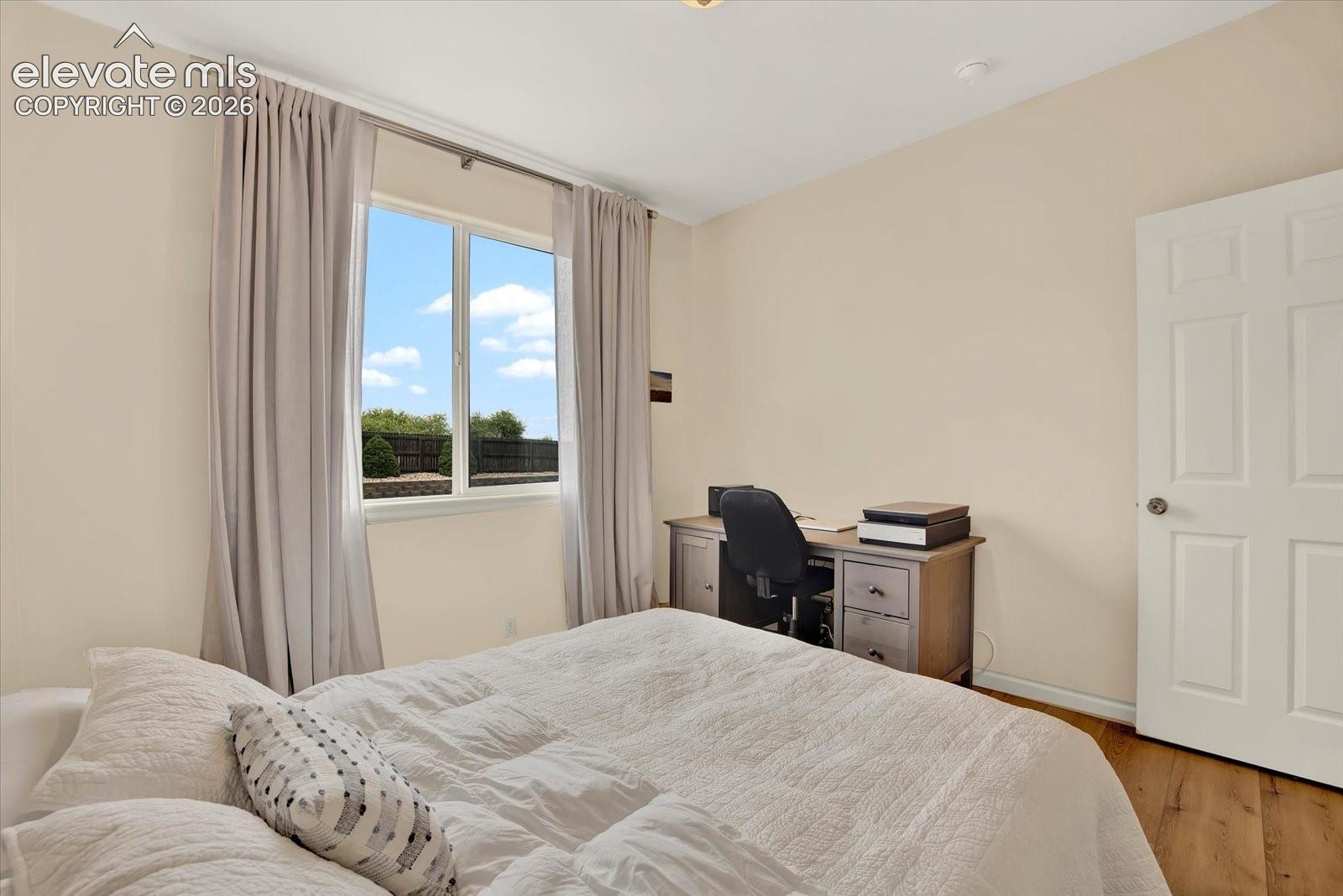 Interior room featuring neutral wall paint, wood-finish flooring, and a single-hung window with a metal curtain rod