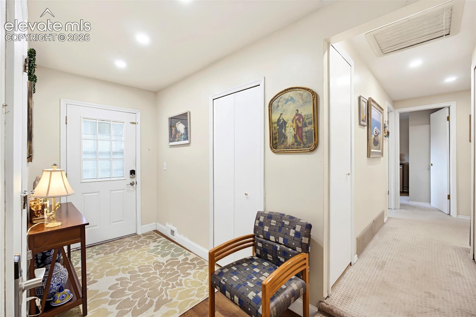 Entryway with a white paneled door featuring a glass insert, recessed lighting, and a closet with bifold doors