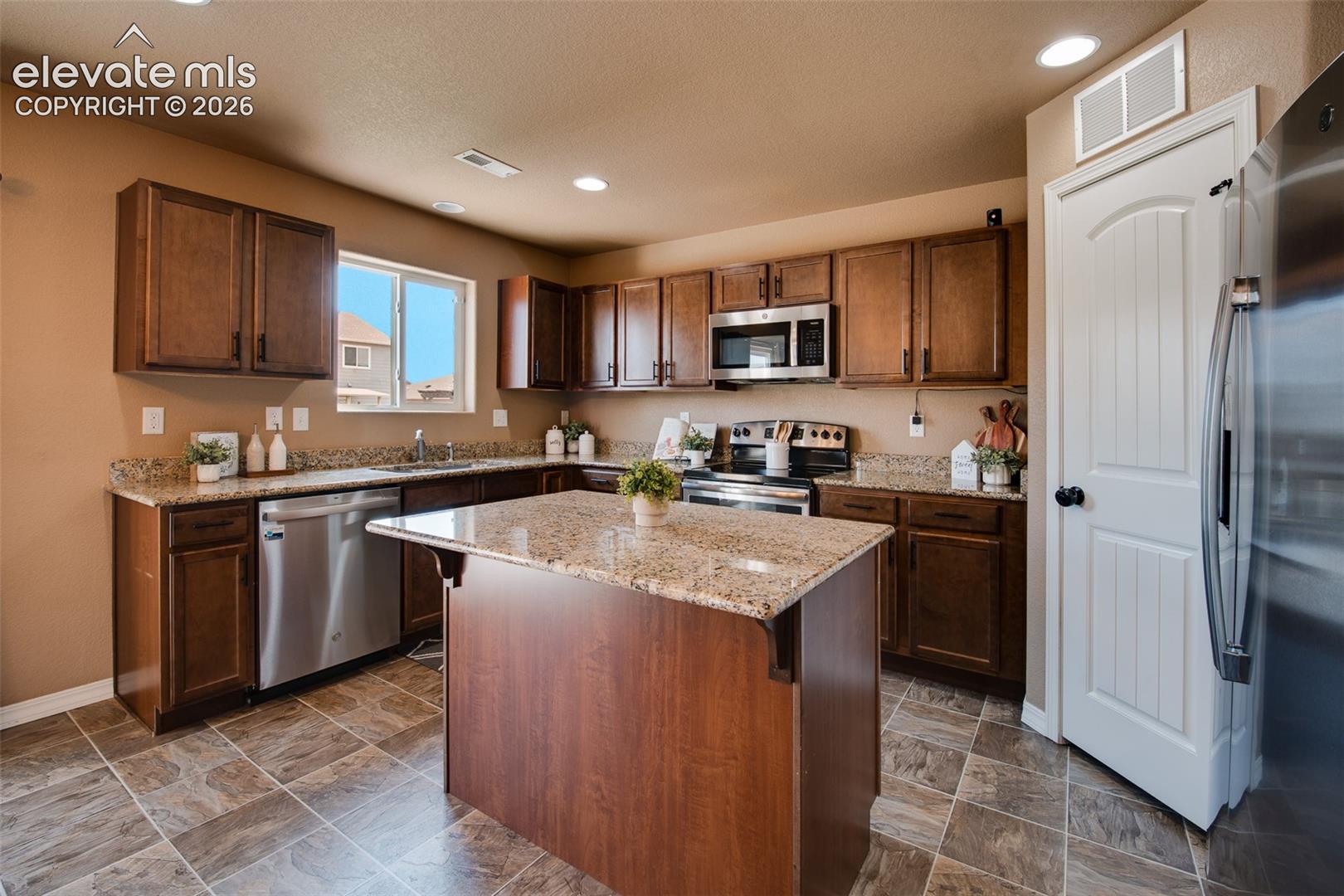 The Island Kitchen features a tile floor, breakfast bar, pantry, and wood cabinets with granite countertops.