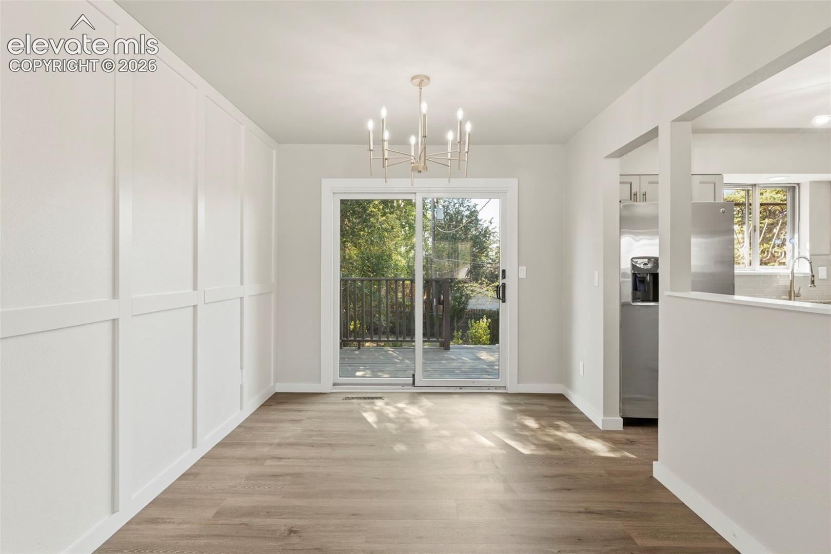 Dining area with luxury vinyl plank flooring, a contemporary chandelier, and board and batten wall detailing