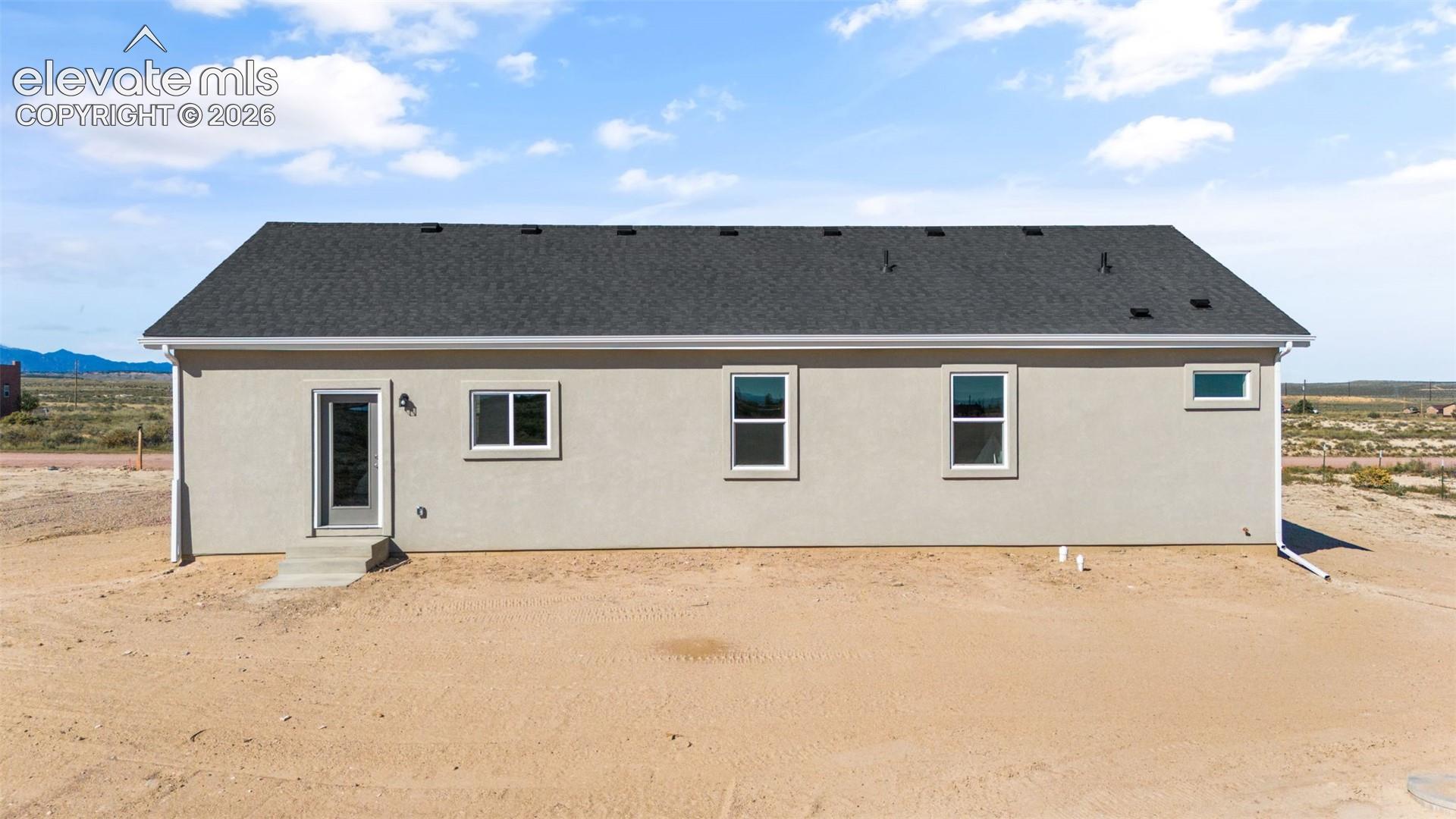 Single-story stucco exterior with a dark shingle roof, white trim, and multiple energy-efficient style windows