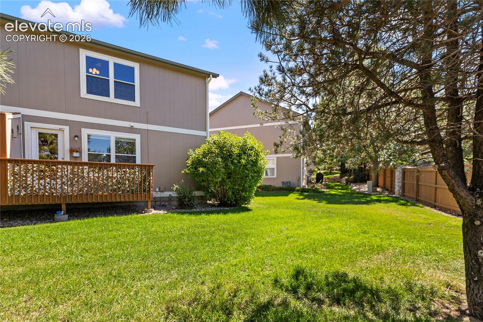 Back yard has open grass area and deck.