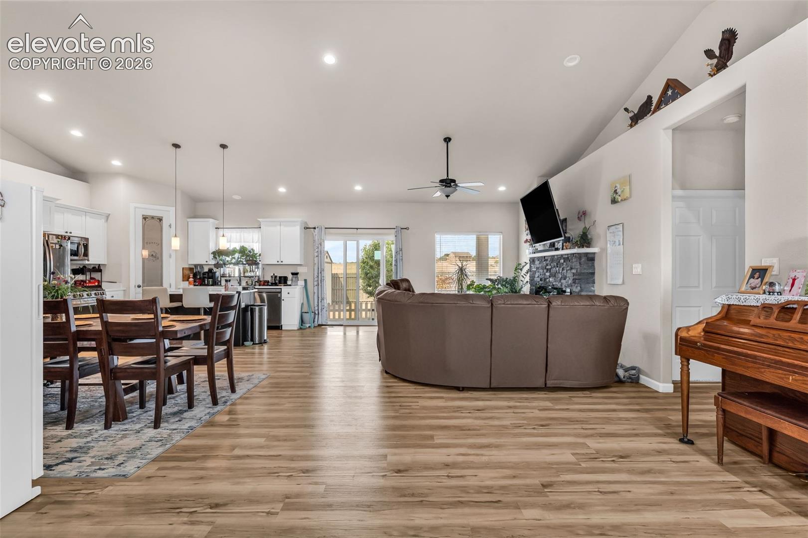Spacious open-concept living area featuring wood-finish flooring and vaulted ceilings