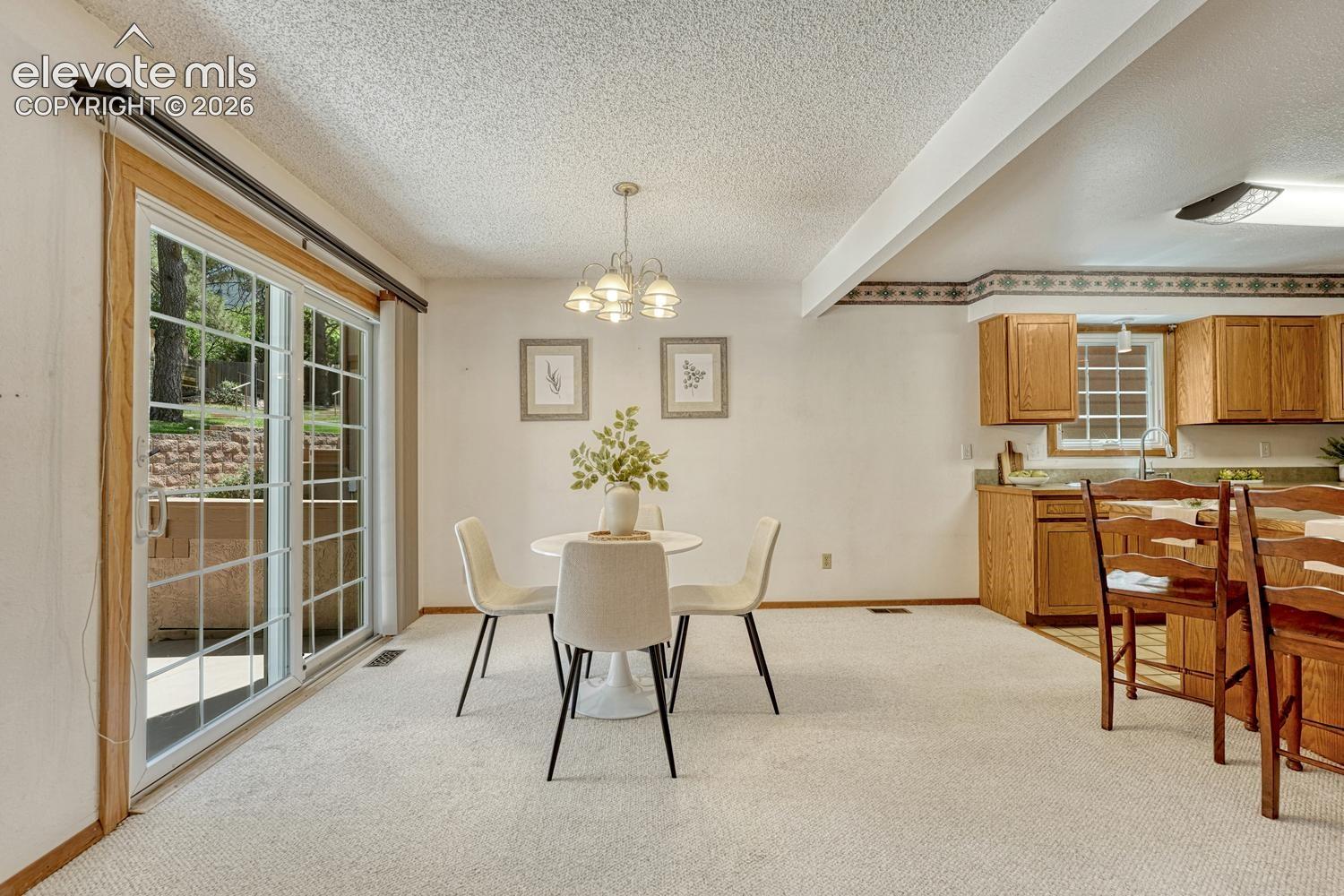 The dining area provides indoor-outdoor living with a wood-framed sliding glass door opening to the front courtyard, perfect for entertaining or outdoor dining.