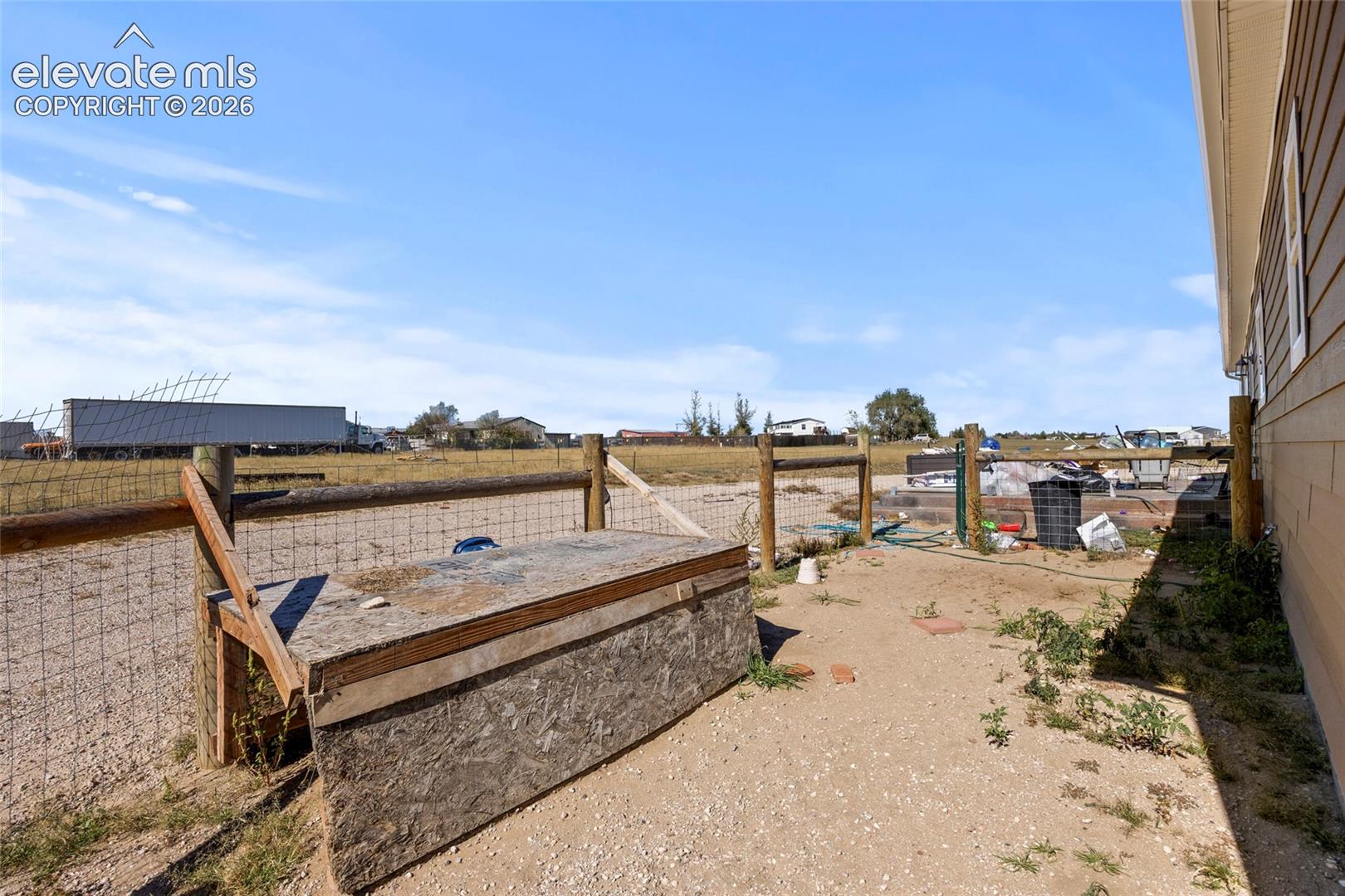 Expansive lot featuring horizontal lap siding, wire and post fencing, and natural terrain