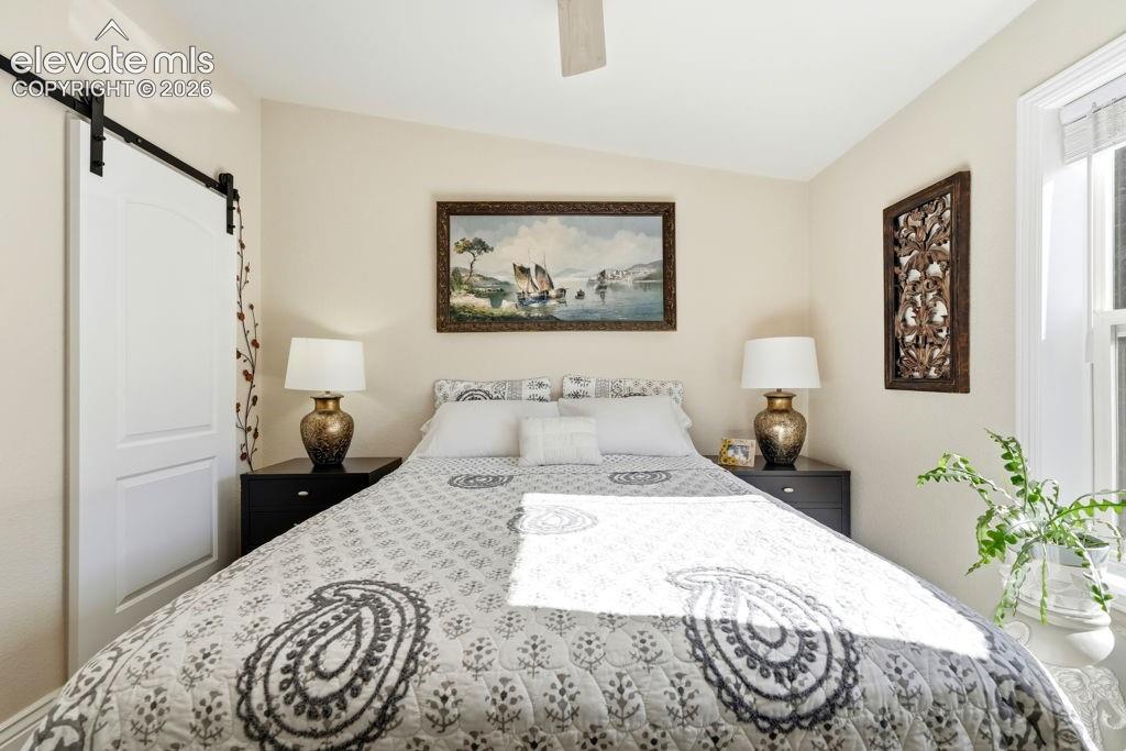 Sliding barn door with black hardware, wall-mounted ceiling fan, and window with white trim