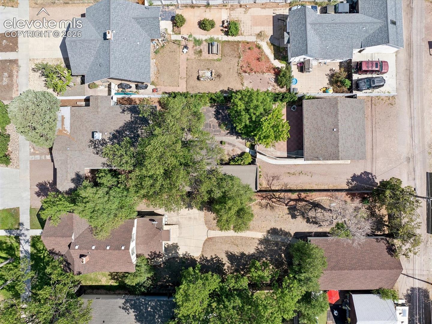 Overhead perspective showcasing a residential property with a shingle roof and mature trees