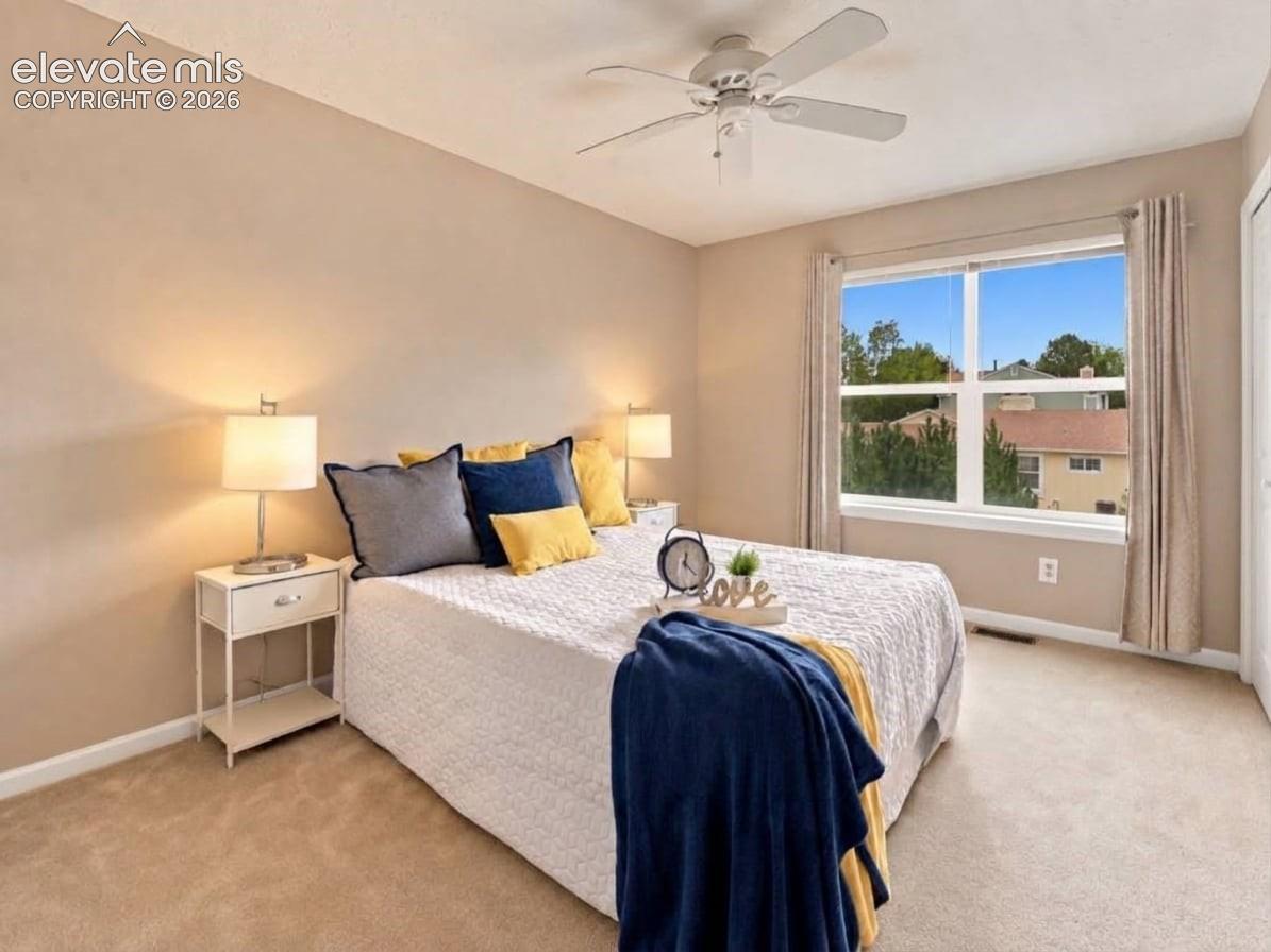 Neutral interior featuring wall-to-wall carpeting, a center-mounted ceiling fan with light fixture, and a window with exterior neighborhood outlook