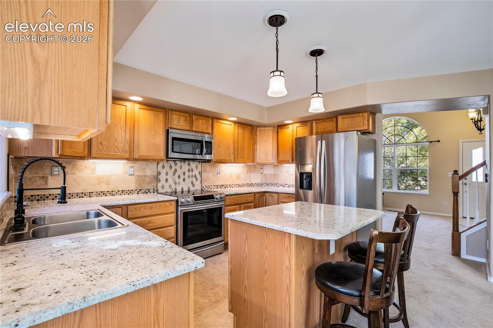 Stainless steel refrigerator, range, built-in microwave + dishwasher complement generous cabinetry, under-cabinet lighting and a convenient kitchen pantry.