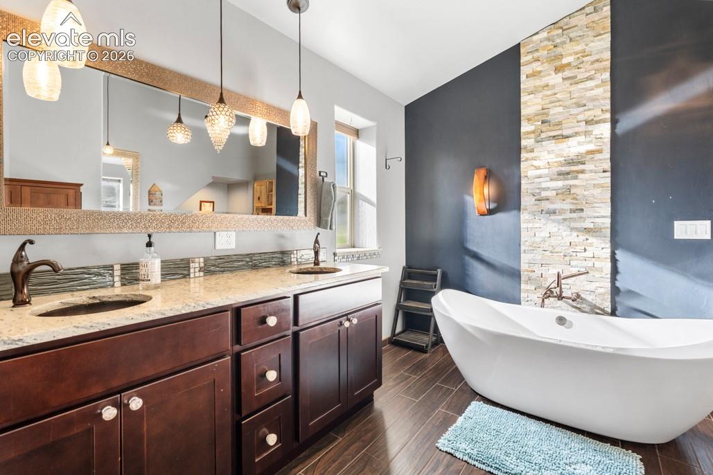 Dual vanity with granite countertops, rich wood cabinetry, and oil-rubbed bronze fixtures