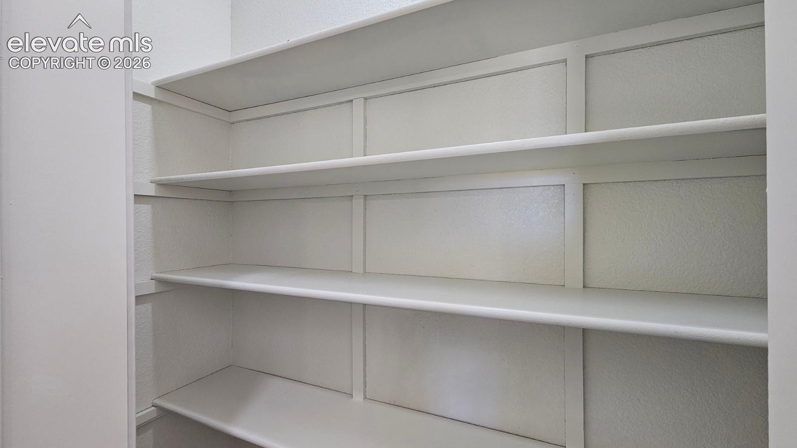 Built-in storage area featuring multiple tiered, painted wood shelving units with vertical support detailing