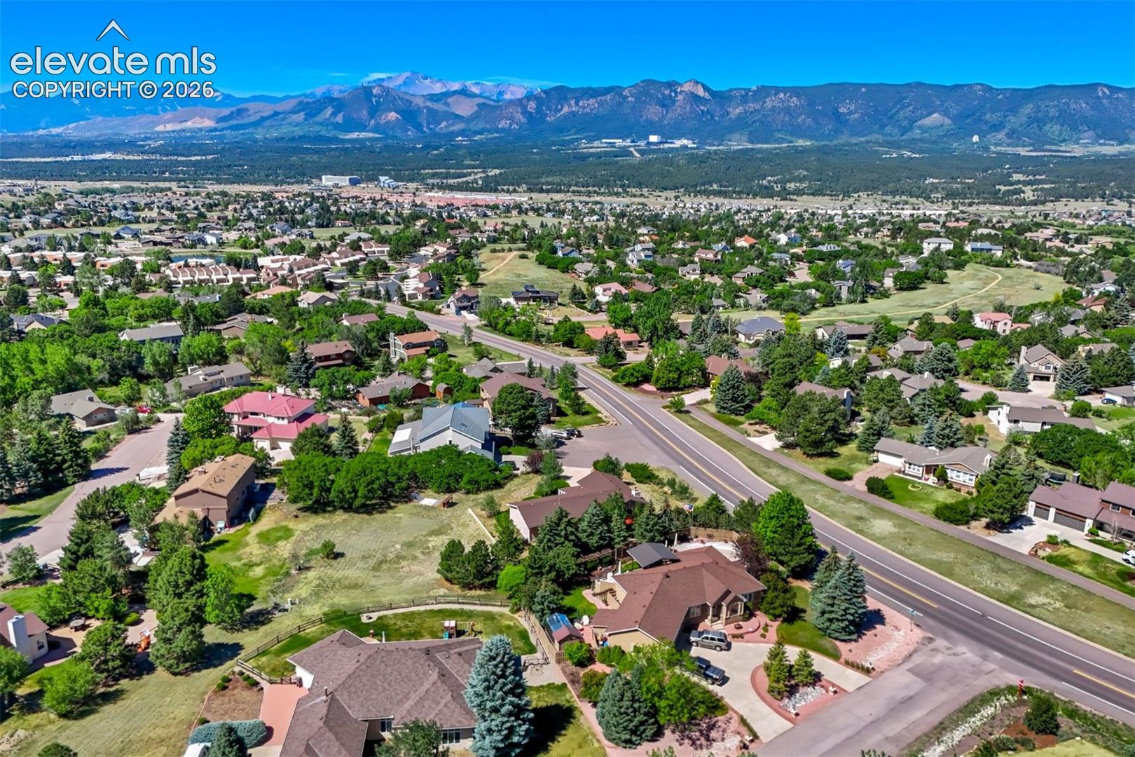Expansive suburban landscape featuring varied architectural styles and mature trees, set against a distant mountain range