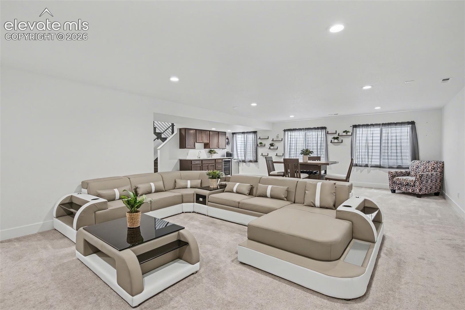 Living room featuring light colored carpet, recessed lighting, and beverage cooler
