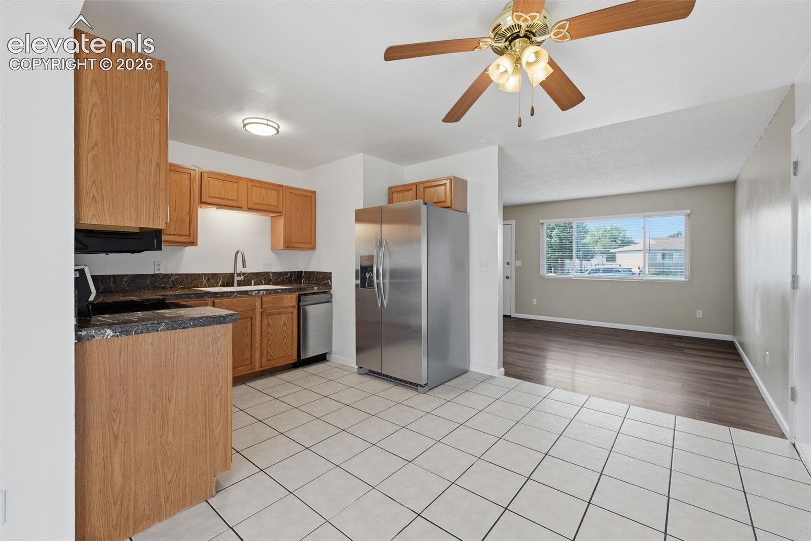 Kitchen featuring wood cabinetry, stone-finish countertops, stainless steel appliances, and tile flooring