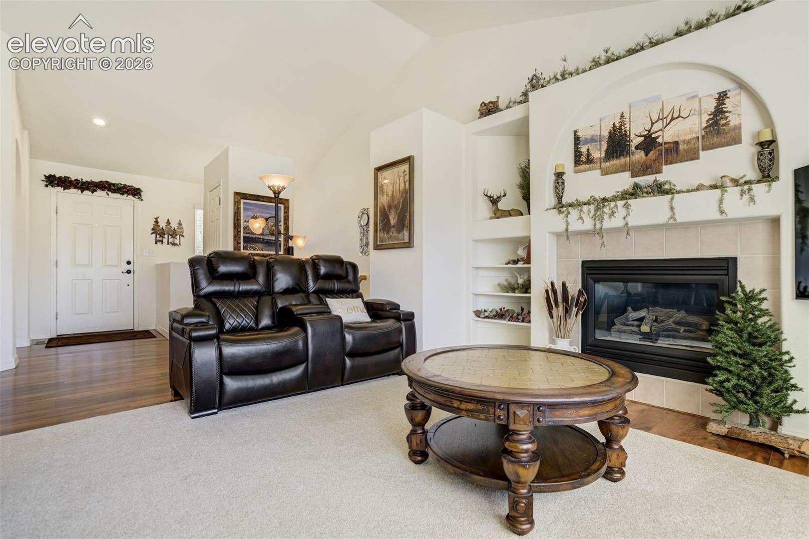 Vaulted ceilings, built-in shelving, tile-surround gas fireplace, and wood-finish flooring