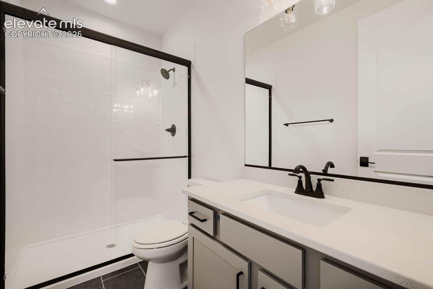 Shower with black-framed glass enclosure, white subway tile surround, and matte black fixtures