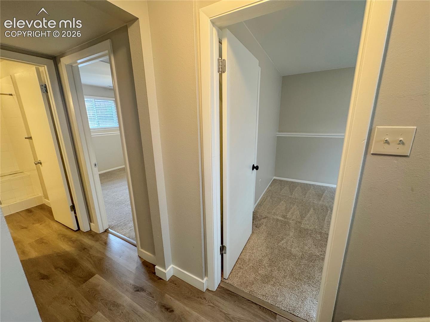 Hallway featuring wood-finish flooring, carpeted flooring, and chair rail molding