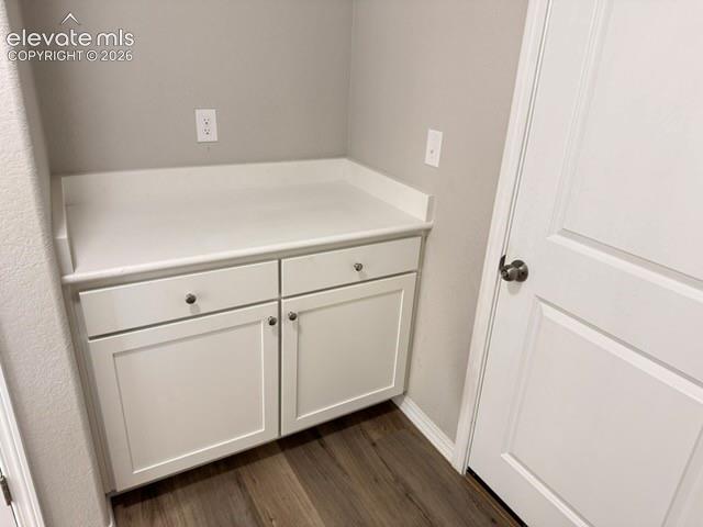 Built-in white cabinetry with a solid surface countertop, two drawers, and two cabinet doors, complemented by wood-finish flooring