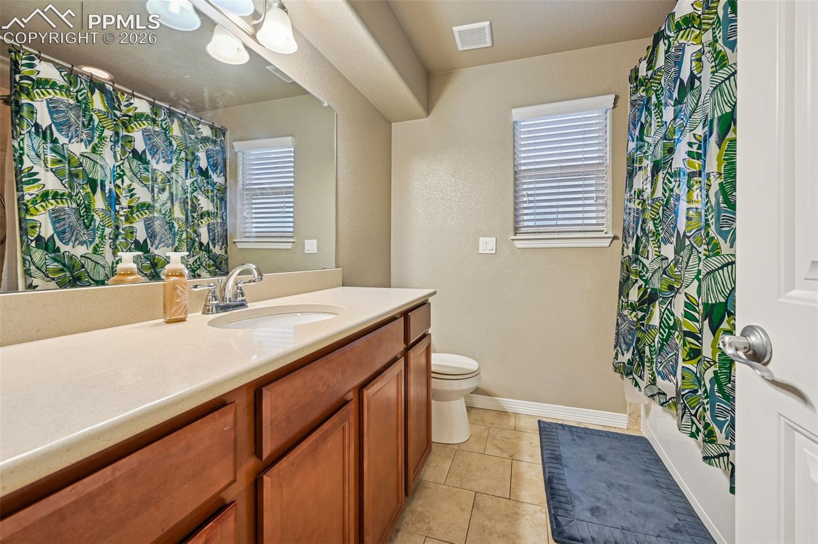 Full bathroom with vanity, light tile patterned floors, and shower / bathtub combination with curtain
