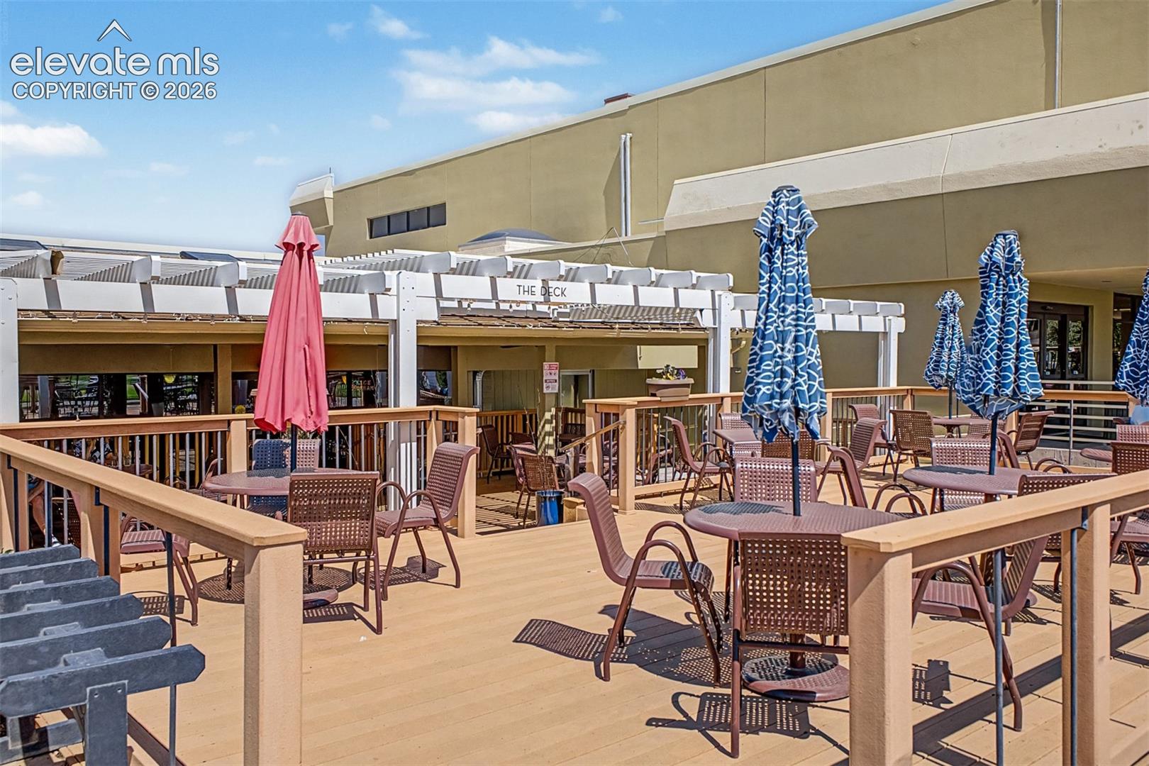 Expansive outdoor deck featuring composite wood-finish flooring, a white pergola structure, and clear railing panels