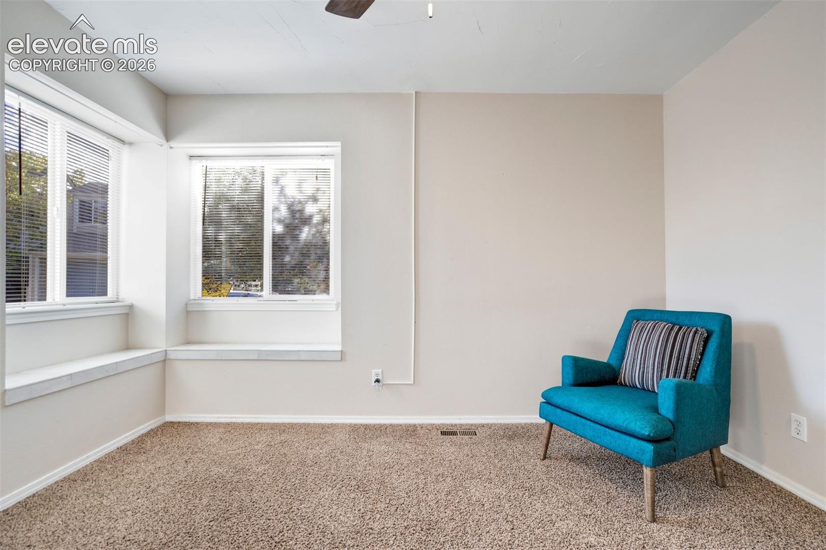 Neutral-toned interior featuring dual windows with built-in ledge seating and wall-to-wall carpeting