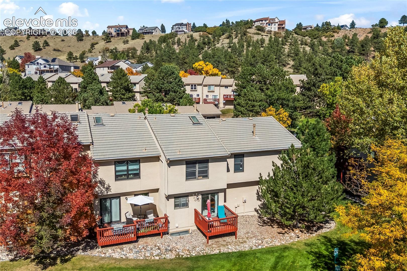Terraced landscaping with two private decks, skylights, stucco exterior, and sloped roof