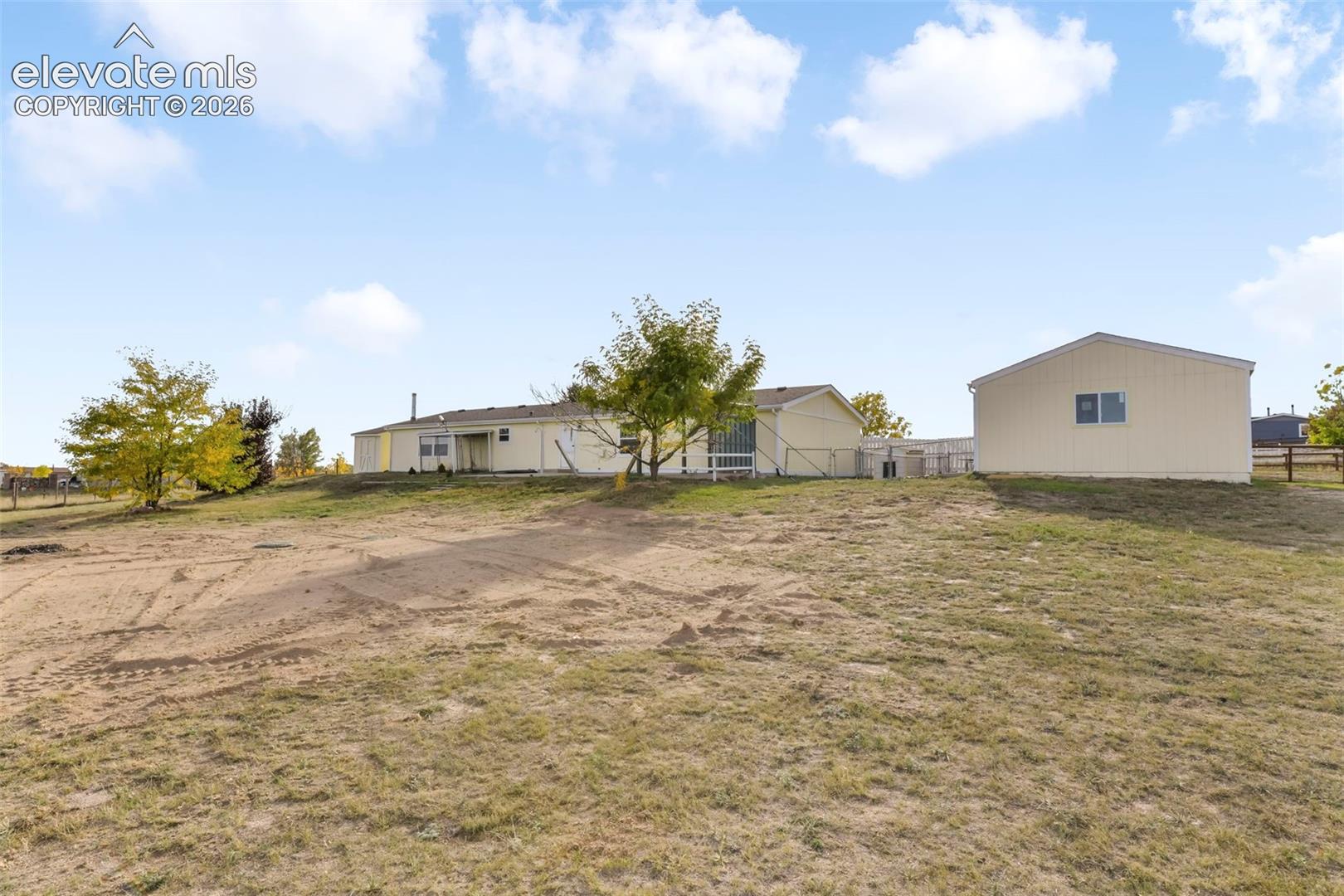 Expansive, undeveloped lot with a separate outbuilding and a detached single-story residence