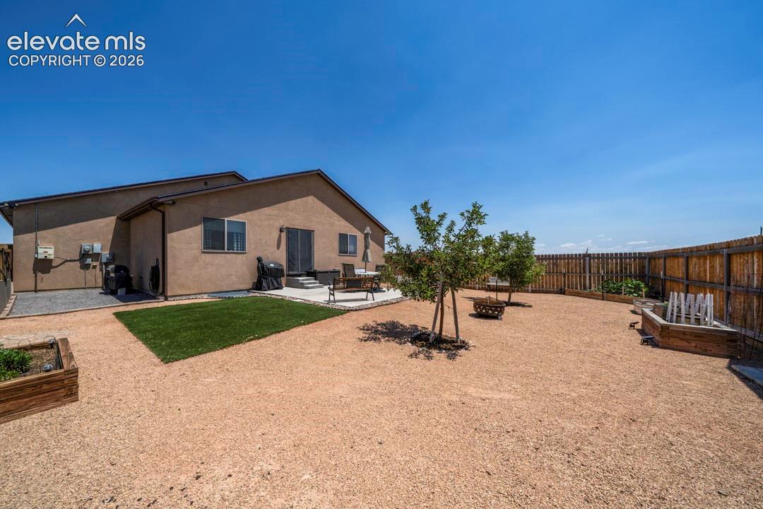 Expansive backyard featuring a gravel landscape, a concrete patio, and a privacy fence