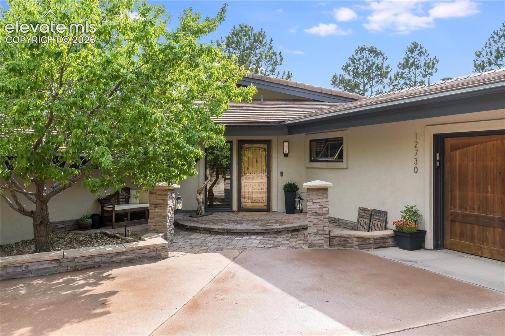 Front entrance featuring a rich wood door, stone facade accents, and a paved entry