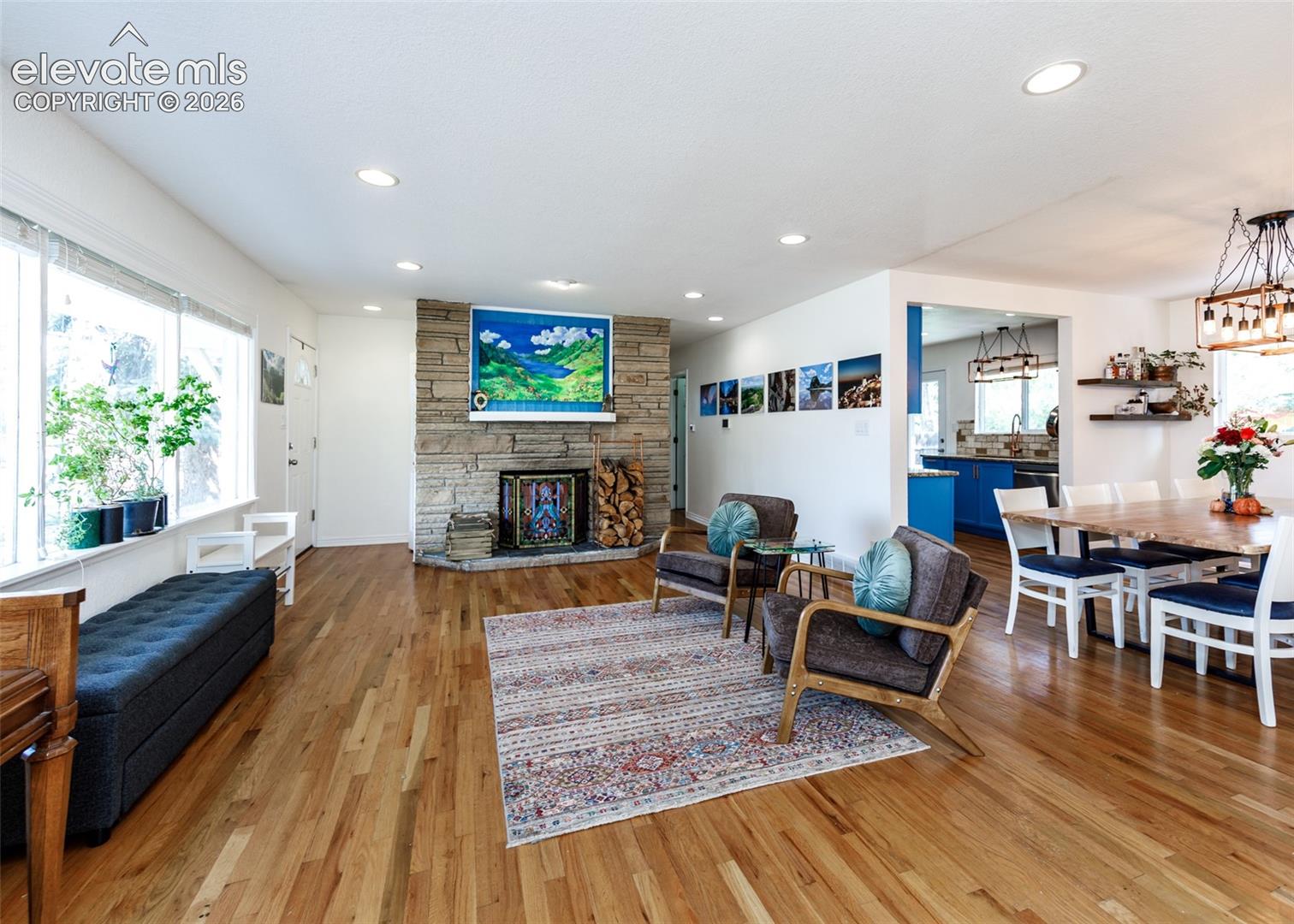 Hardwood flooring, stone-clad fireplace, recessed lighting, expansive windows, open-concept layout