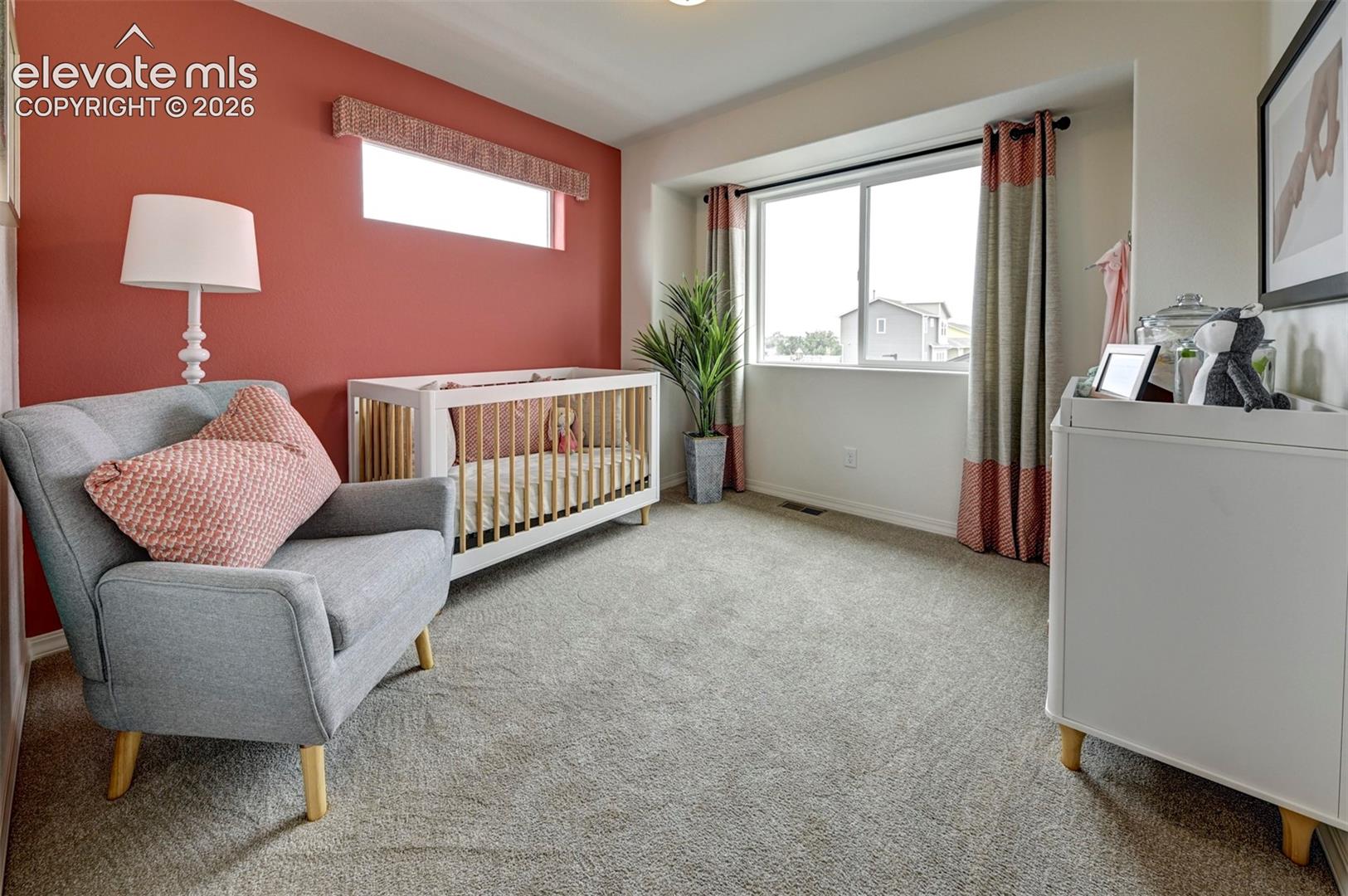 Room featuring carpeting, a horizontal transom window, a sliding glass window set within a recessed alcove, and an accent wall