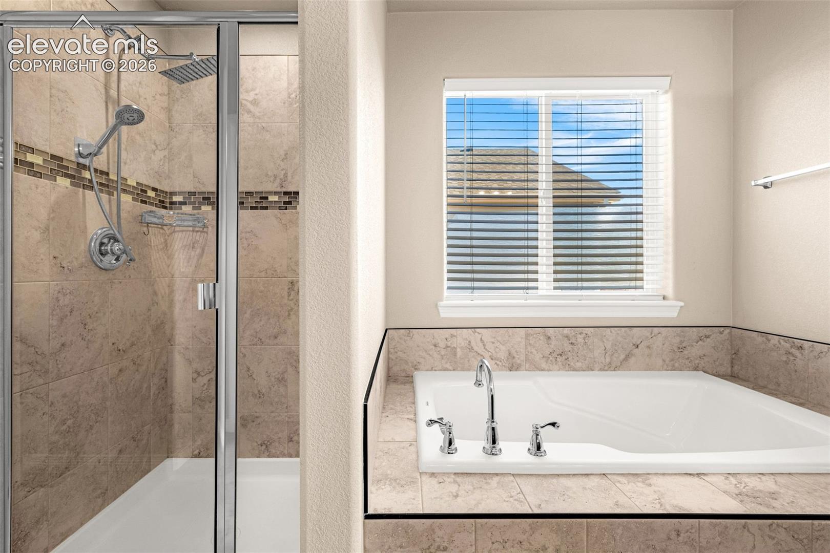 Tiled walk-in shower with glass enclosure, dual shower heads, and decorative accent tiles
