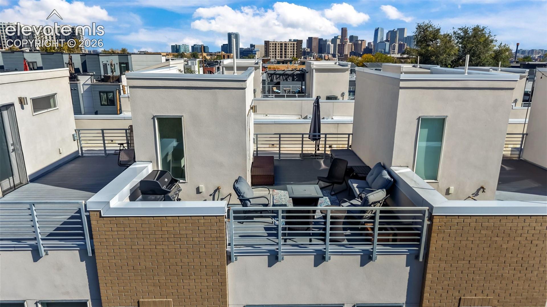 Rooftop deck featuring concrete-finish flooring, metal railing, and cityscape backdrop