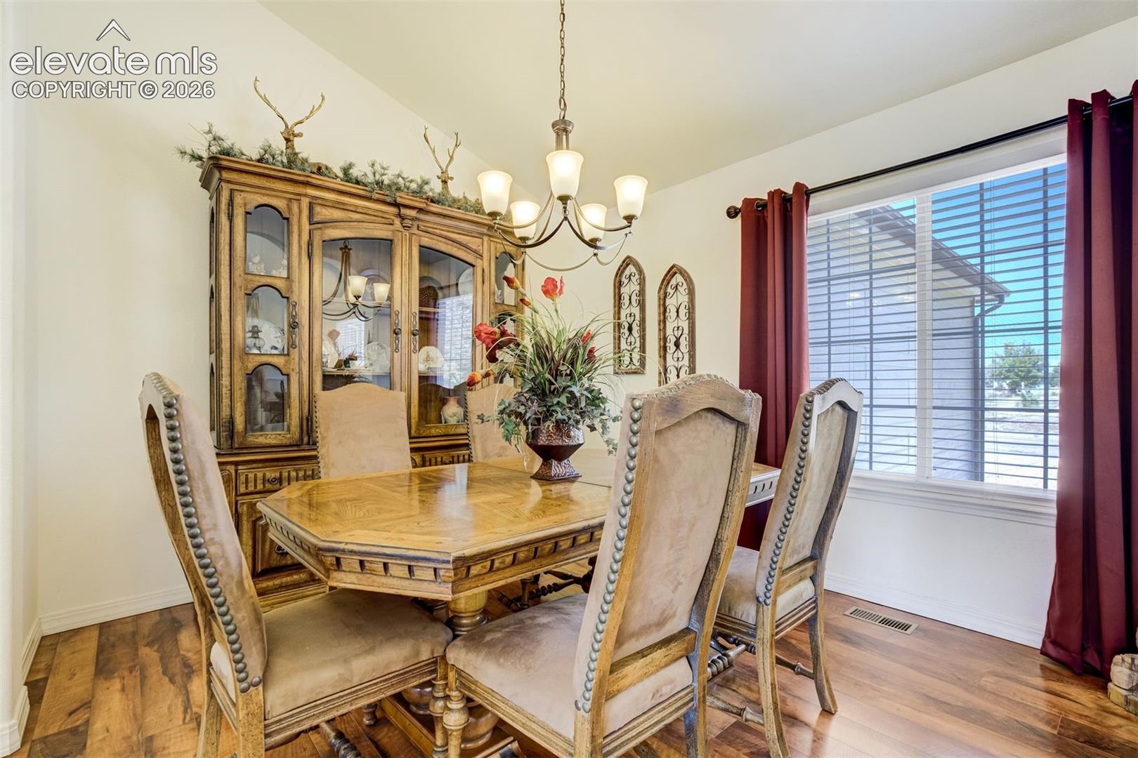 Dining room featuring wood-finish flooring, a multi-light chandelier, and a large window with natural light