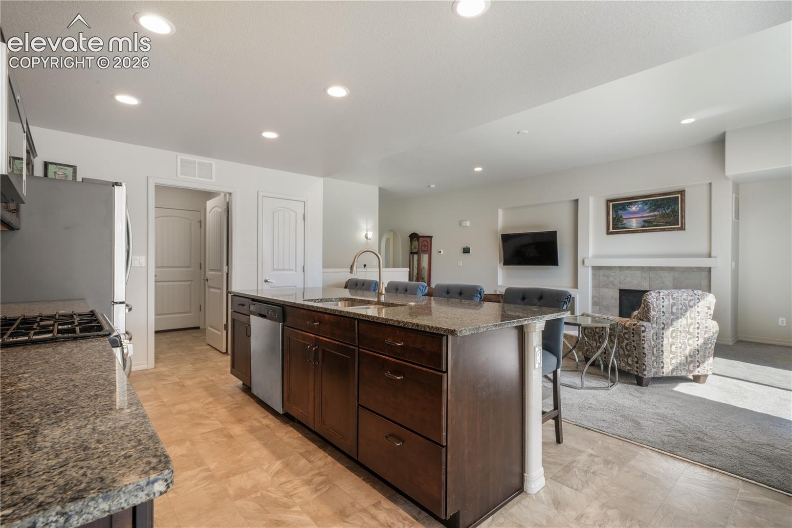 Kitchen with large island, granite countertops, gas range, abundant cabinets, views into living room