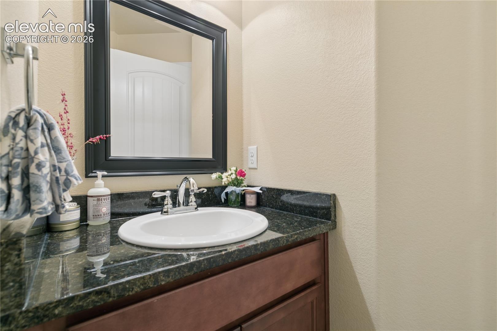 Vanity featuring a dark stone countertop, undermount sink, and chrome faucet