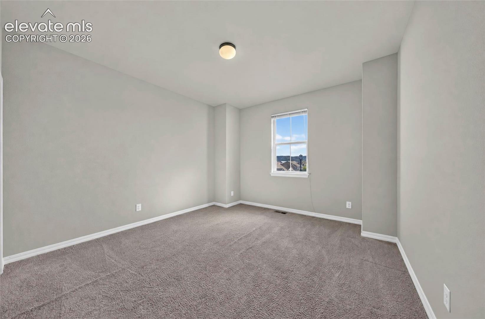 Neutral wall finishes, plush carpet flooring, recessed window, and overhead lighting
