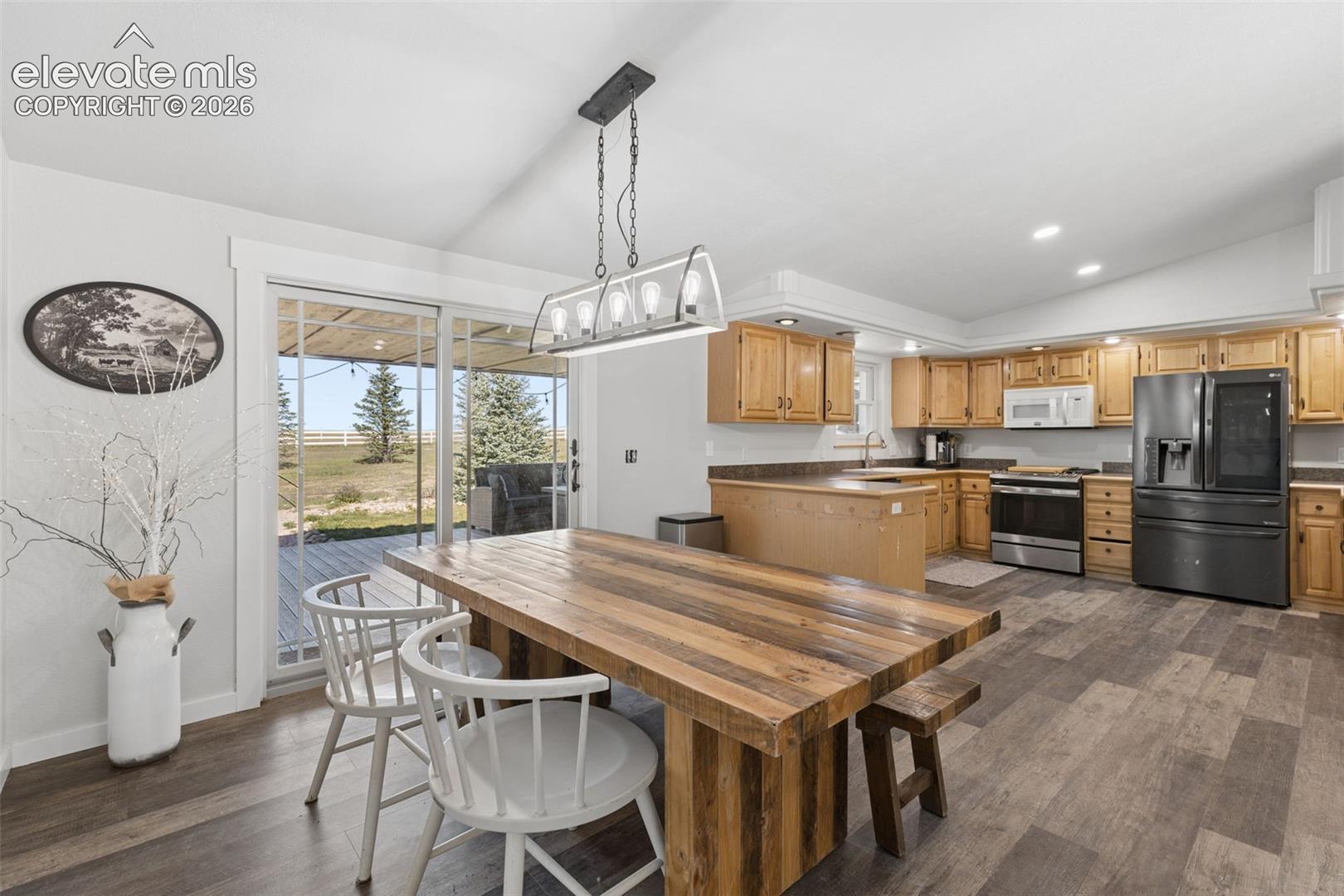 Kitchen featuring wood cabinetry, stainless steel appliances, wood-finish flooring, a rectangular pendant light fixture, and glass sliding doors