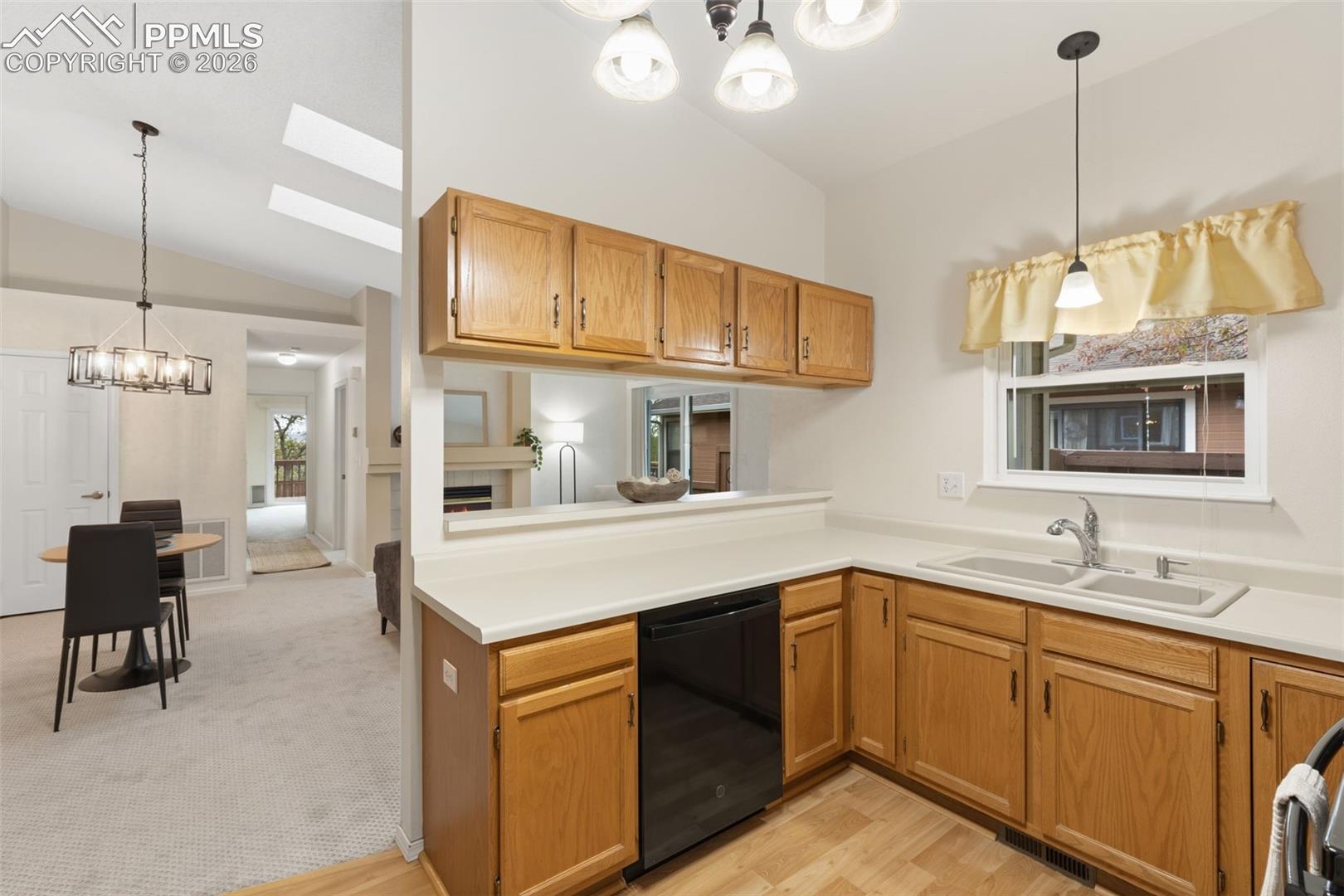The kitchen features wood cabinetry, a double basin sink, and a dishwasher