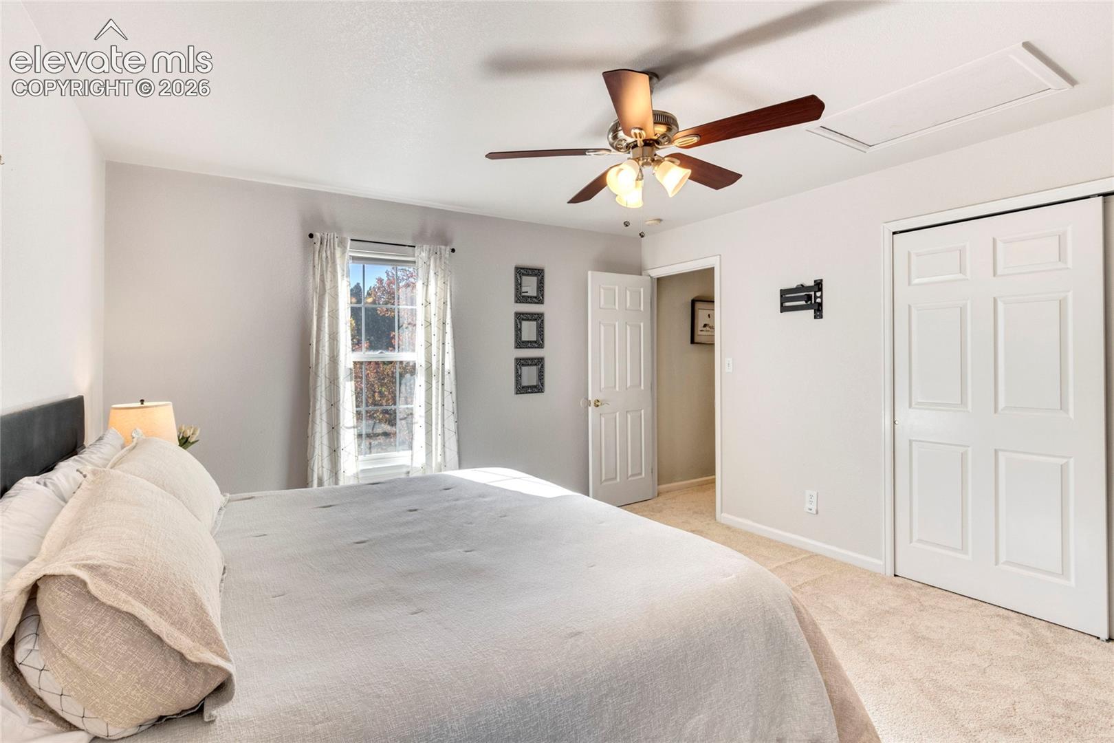 Bedroom featuring wall-to-wall carpeting, a ceiling fan with integrated lighting, and a six-panel closet door