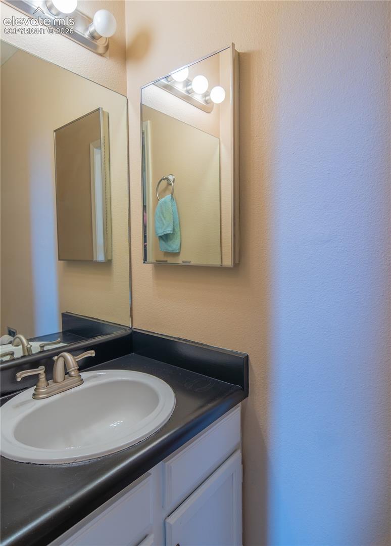 White vanity with dark countertop, undermount sink, and brushed nickel faucet