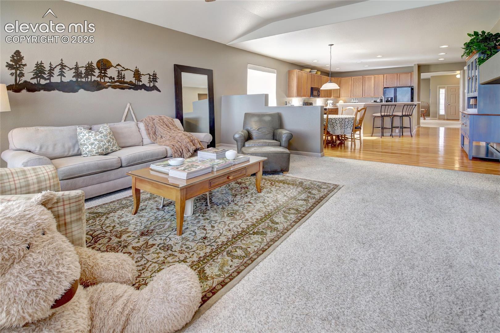 Vaulted ceilings, neutral wall tones, recessed lighting, wood-finish flooring, and cabinetry with integrated peninsula