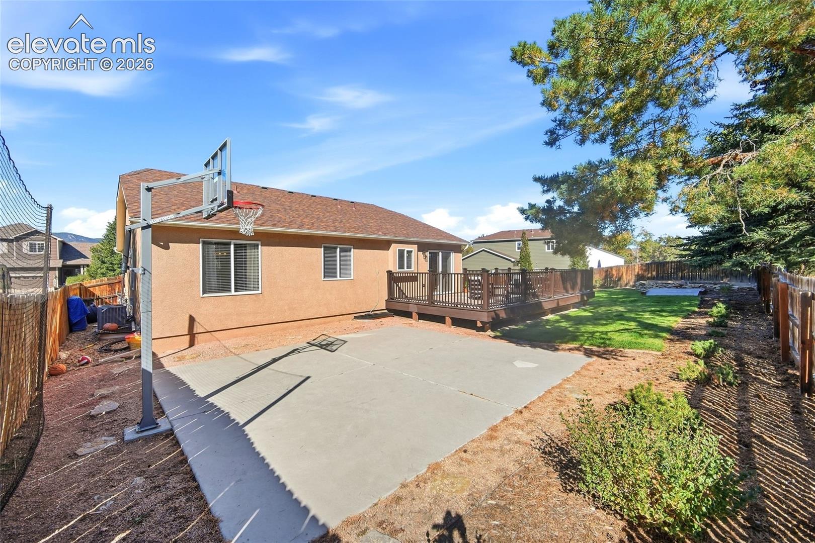 Expansive backyard featuring a large concrete patio, a multi-level wood deck, and a grass lawn