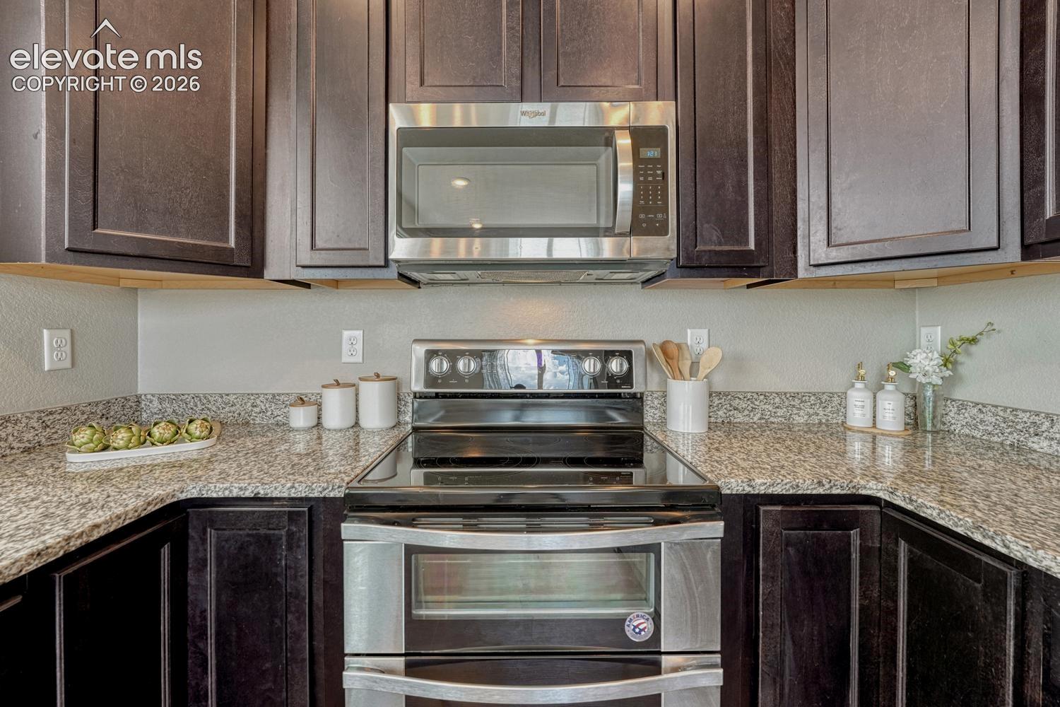 Stainless steel appliances include a smooth top range with double oven, microwave, dishwasher, and side by side refrigerator.