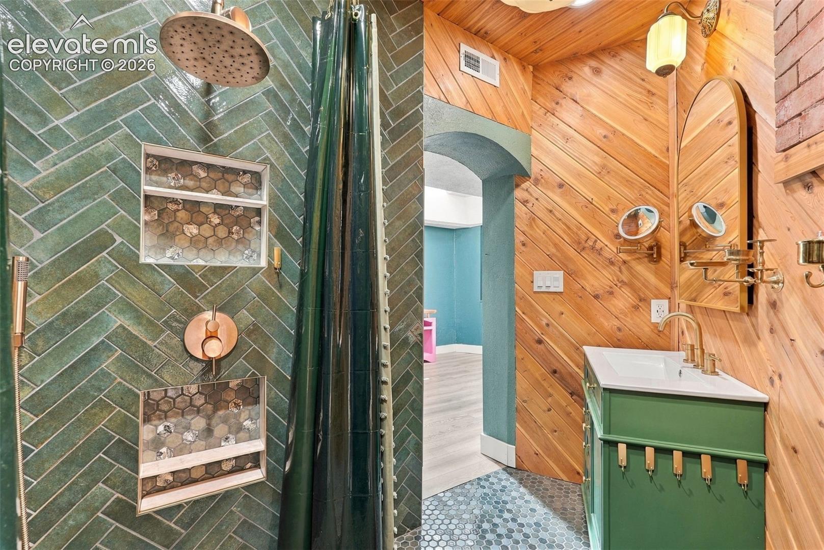 Spa Shower with herringbone-patterned green tile shower with copper-toned fixtures and mosaic-tiled niches